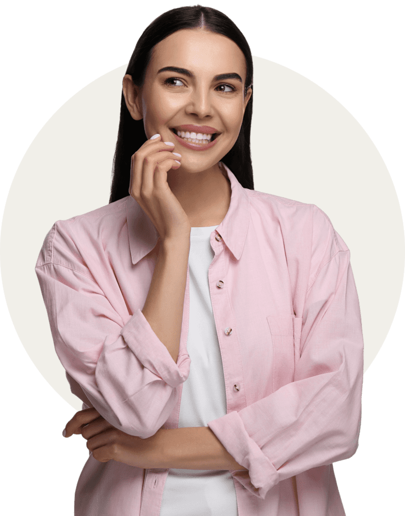 A person in a pink shirt smiles while looking to the side. Their hand rests on their chin against a neutral background.
